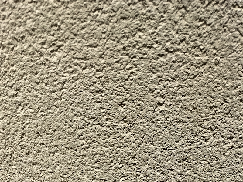 Gros plan sur une finition d’enduit gratté à l’aspect texturé, typique des façades extérieures.